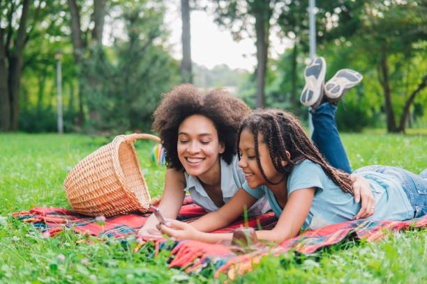 istock Happy girls using mobile phone while having a picnic 1022932266