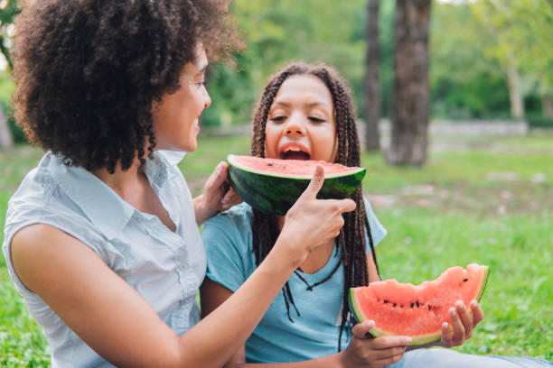 istock Young woman feeding her daughter watermelon 1022932800