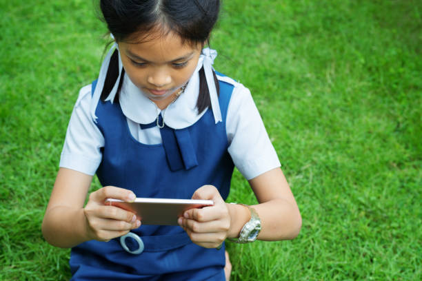 cute little girls playing internet with mobile smartphone on grass