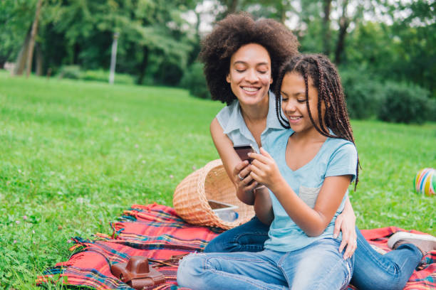 istock Happy girls using mobile phone on a picnic 1022943280