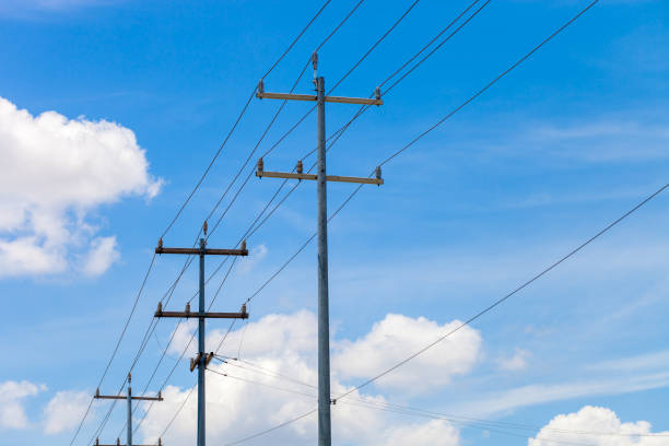 Multi-purpose utility poles with blue sky and clouds in the background stock photo