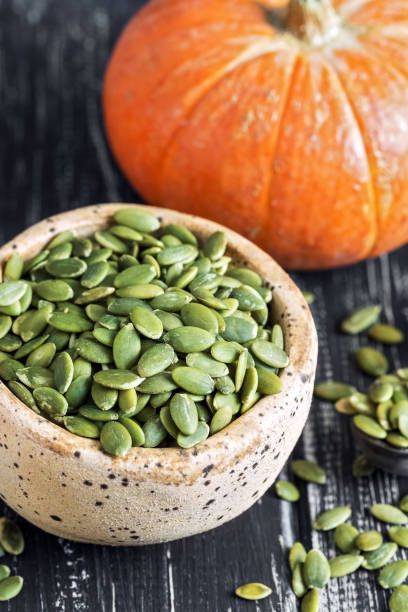 istock Bowl with green pumpkin seeds close-up on a wooden rustic table. Selective focus. 1022963186