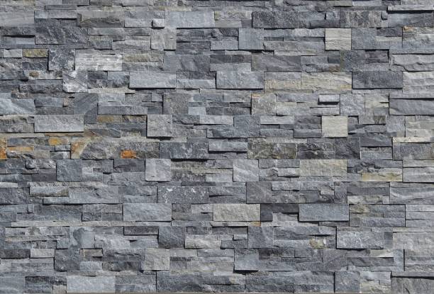 istock Grey stone wall cladding made of strips and square blocks stacked . Background and texture. 1022963396