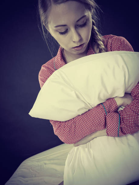 istock Sad depressed girl in bed gripping pillow 1022982112