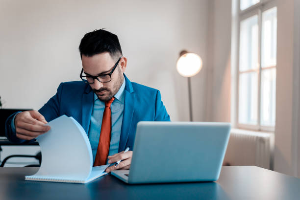 istock Handsome young man in a suit looking at documents, sitting in the office. 1022990952