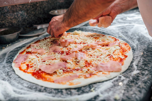 istock Adding salami on the pizza. Close-up. 1022991762