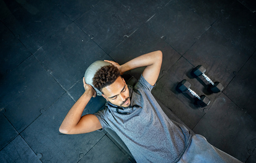 Handsome black man lying on floor working out with a med ball his abs looking focused