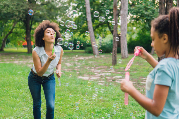 istock Happy young woman blowing soap bubbles at her daughter 1023026076