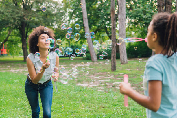 istock Young woman using bubble wand in the park 1023026102