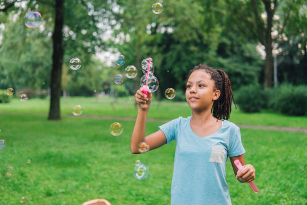 istock Young girl looking at bubble wand in her hands 1023026344
