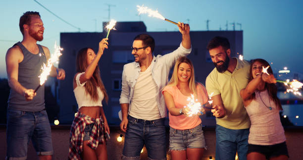 istock Friends enjoying rooftop party with sparklers 1023035544