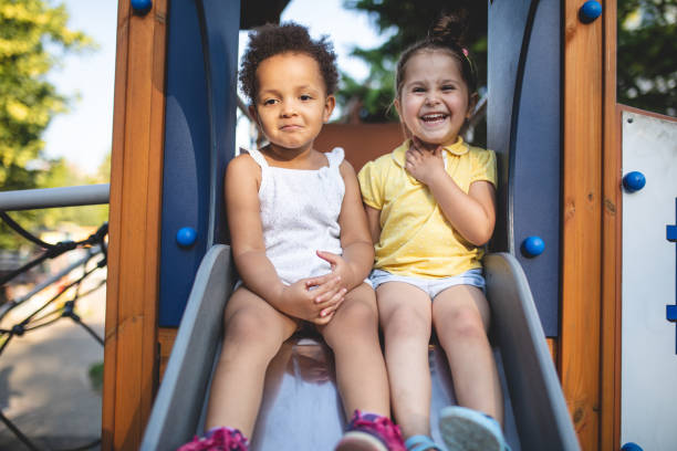 istock Cute smiling siblings sitting on a playground slide 1023035552