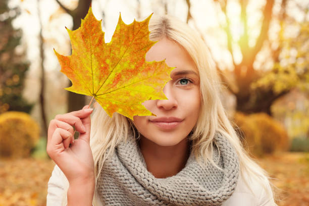 istock Young woman with fall leaf outdoors in autumn park 1023035806