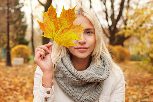 Autumn woman with fall leaf walking outdoors