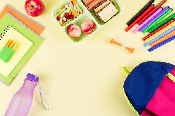 istock School concept flat lay. Kid backpack, lunchbox, water bottle, notebook, markers on wooden desktop 1023037960