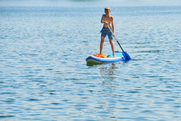 istock Paddle boarder. Child boy paddling on stand up paddleboard 1023038496