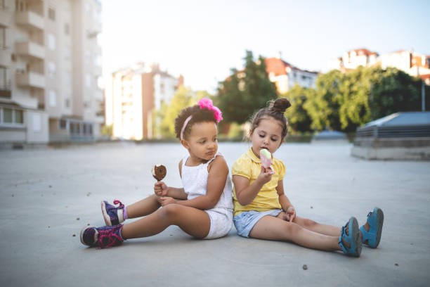 прекрасные откровенные дети едят мороженое вместе - child looking messy urban scene стоковые фото и изображения