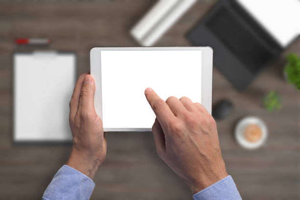 istock Man holding tablet knolling overhead view 1023042542