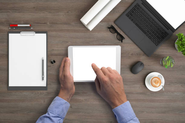 istock Man holding tablet knolling overhead view 1023042550