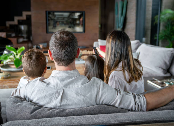 volverver de familia en su casa viendo la televisión mientras mamá cambia canales - apartment television family couple fotografías e imágenes de stock