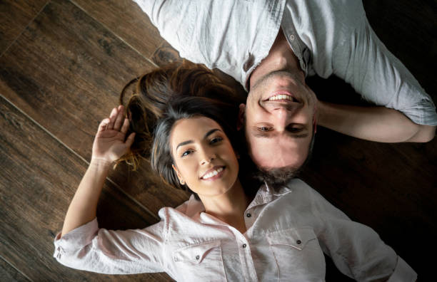 istock Sweet couple lying down on the floor looking at camera smiling 1023053368