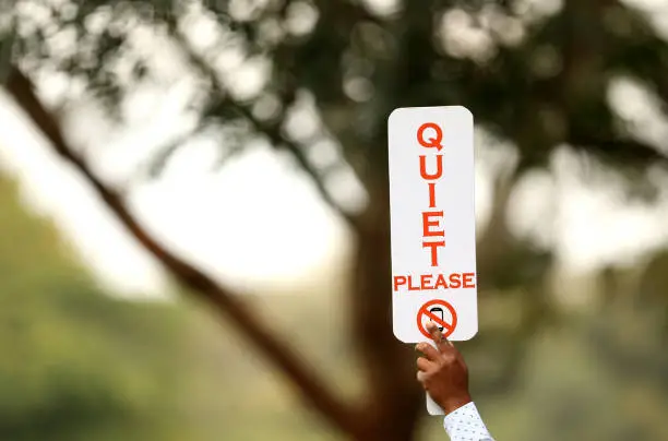 A quiet sign held up at a golf tournament