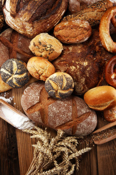 istock Different kinds of bread and bread rolls on board from above. Kitchen or bakery 1023073698