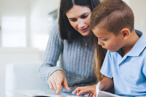 boy getting tutored with school assignment Young boy receiving one on one help with assignment. elementary student with teacher stock pictures, royalty-free photos & images