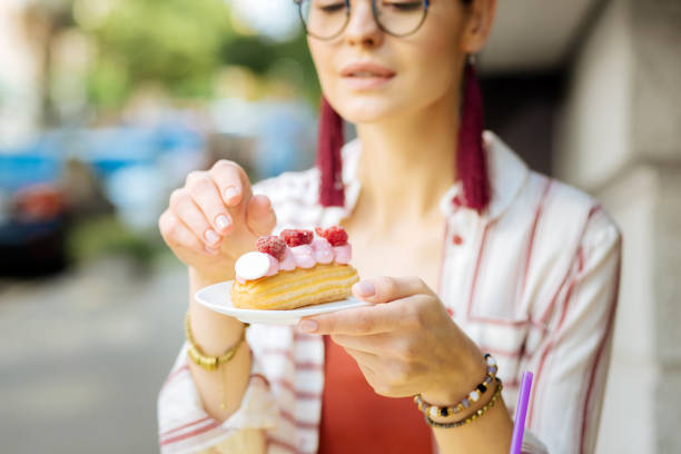 istock Curious woman holding a plate and looking at the eclair on it 1023115248