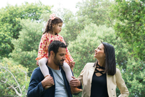 Family playing in the park Family, Latina, with their parents between 25 and 30 years old and a little girl between 3 and 5 years old, playing happily, while the Pope holds the little girl on her shoulders niñas stock pictures, royalty-free photos & images