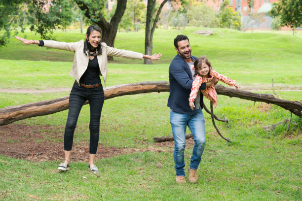 Family playing in the park Family latin, parents between 25 and 30 years old and a small girl between 3 and 5 years old, happily playing the little plane in the park, all smile niñas stock pictures, royalty-free photos & images