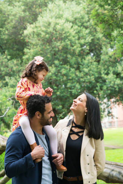 Family playing in the park Family, Latina, with their parents between 25 and 30 years old and a little girl between 3 and 5 years old, playing happily, while the Pope holds the little girl on her shoulders niñas stock pictures, royalty-free photos & images