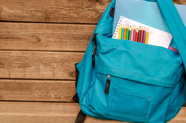 istock Blue school Back pack with pencils and note book on wooden board.Front view with copy space 1023131210