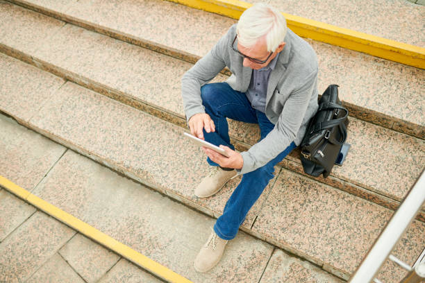 istock Aged businessman with tablet on stairs 1023140292