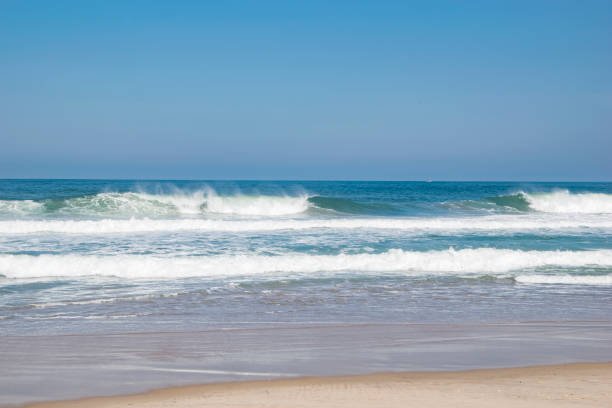 istock Sunny day on the beach with wave breaking off shore wind 1023145132