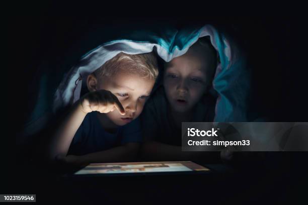 Dos Niños Con Tablet Pc En Una Habitación Oscura Foto de stock y más banco de imágenes de Niño - Niño, Internet, Seguridad