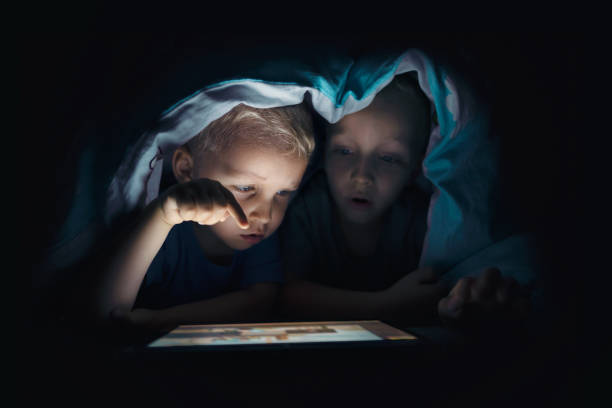 istock Two kids with tablet computer in a dark room 1023159546