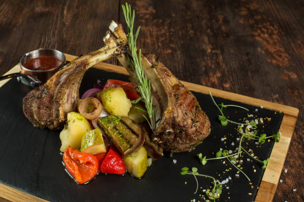 istock Lamb ribs grilled on cutting board with roasted vegetables. 1023172308