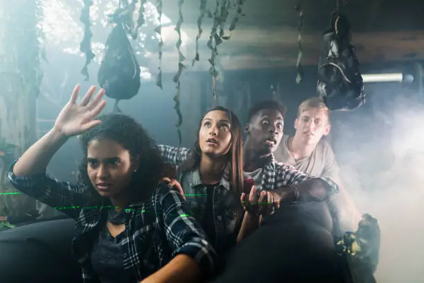 A group of four multi-ethnic teenagers and young adults in a halloween haunted house, on a ride through a dark, creepy tunnel.