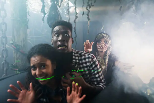 Photo of Young couple with zombie in halloween haunted house