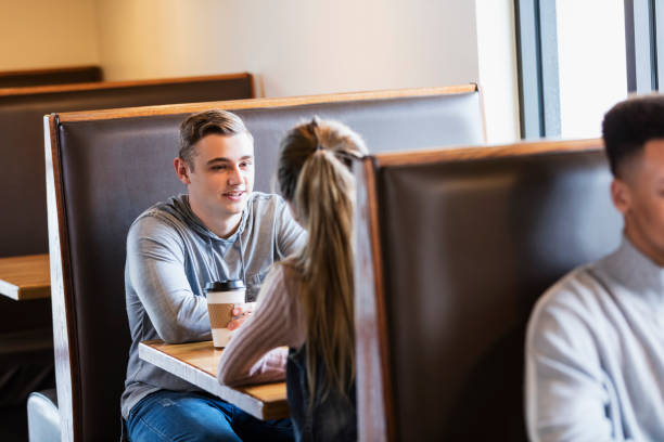 istock Young couple sitting in restaurant booth, conversing 1023211936