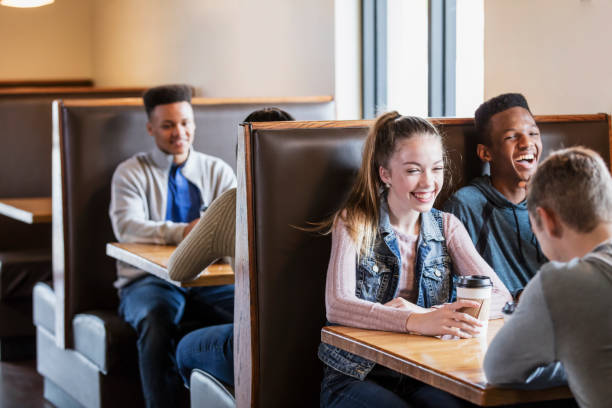istock Teenagers sitting in restaurant booths, conversing 1023211982