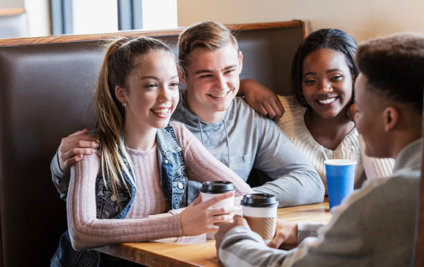 istock Four teenagers sitting in restaurant booth, conversing 1023212162