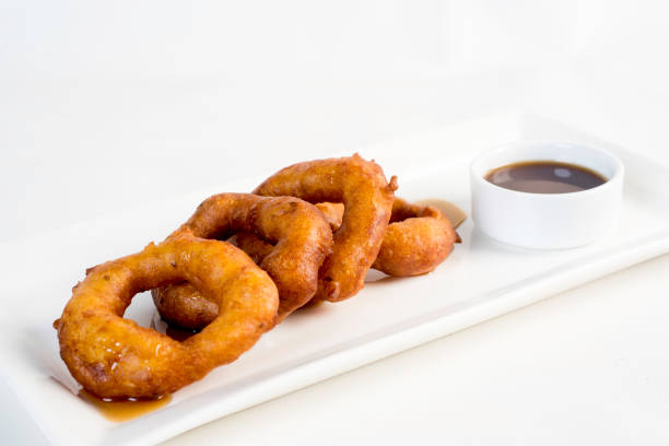 picarones: estos son en forma de anillo de postre hecho con masa de harina de trigo mezclada con zapallo y camote. higos fritos y sumergido en melaza. - sausage shaped fotografías e imágenes de stock