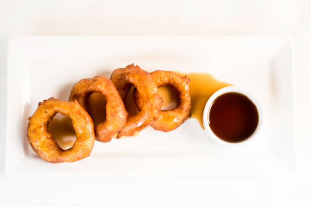 picarones: estos son en forma de anillo de postre hecho con masa de harina de trigo mezclada con zapallo y camote. higos fritos y sumergido en melaza. - sausage shaped fotografías e imágenes de stock