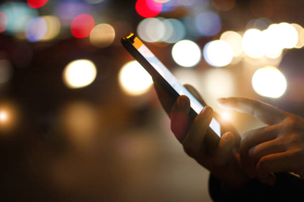 istock Close up female hands using mobile smartphone in illuminated color light bokeh on street night background 1023226420