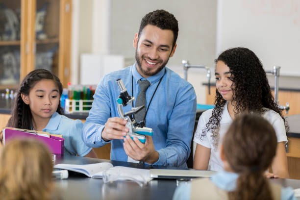 istock Male science teacher shows microscope to students 1023229700