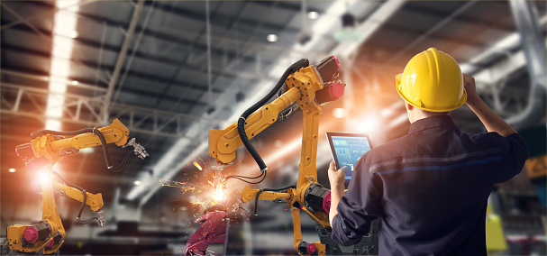 Ingeniero utilizando tablet y controlar automatización robot brazos máquina en fábrica inteligente industrial sobre el control de software del sistema. Soldadura robótica y operación de fabricación digital. photo