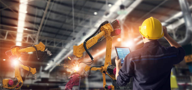 エンジニアのタブレットのチェックを使用して、インテリジェントな工場監視システム ソフトウェアの産業オートメーション ロボット腕機を制御します。溶接ロボット、デジタル製造工程� - manufacturing industry welding engineering ストックフォトと画像