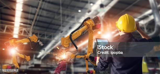 Engineer Using Tablet Check And Control Automation Robot Arms Machine In Intelligent Factory Industrial On Monitoring System Software Welding Robotics And Digital Manufacturing Operation Stock Photo - Download Image Now